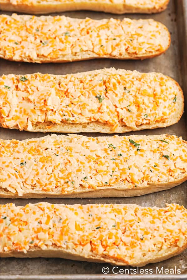 Raw cheesy bread on a baking sheet