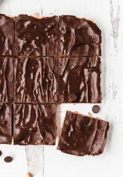 Peanut butter rice krispie treats cut into squares on a marble board with chocolate chips