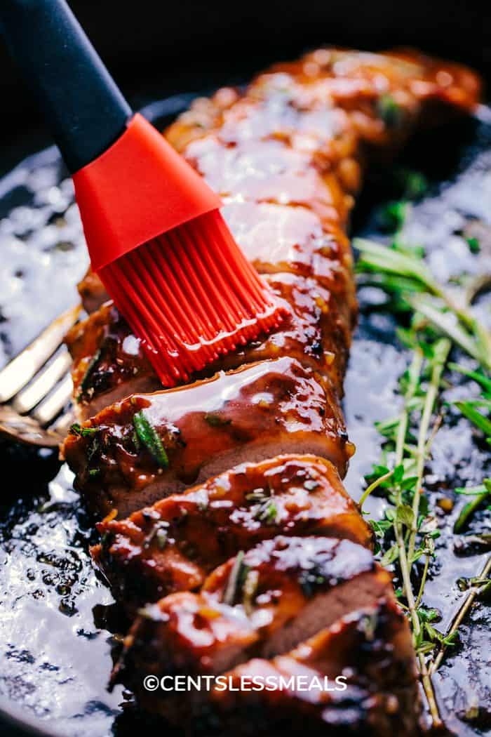 The homemade sauce being applied to the Honey Garlic Roasted Pork Tenderloin