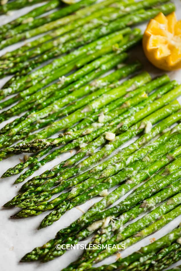 Oven Roasted Asparagus lined up on parchment paper.