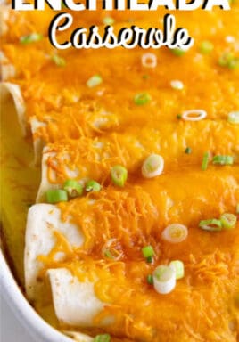 Breakfast Enchiladas garnished with green onion and baked in a white casserole dish with writing