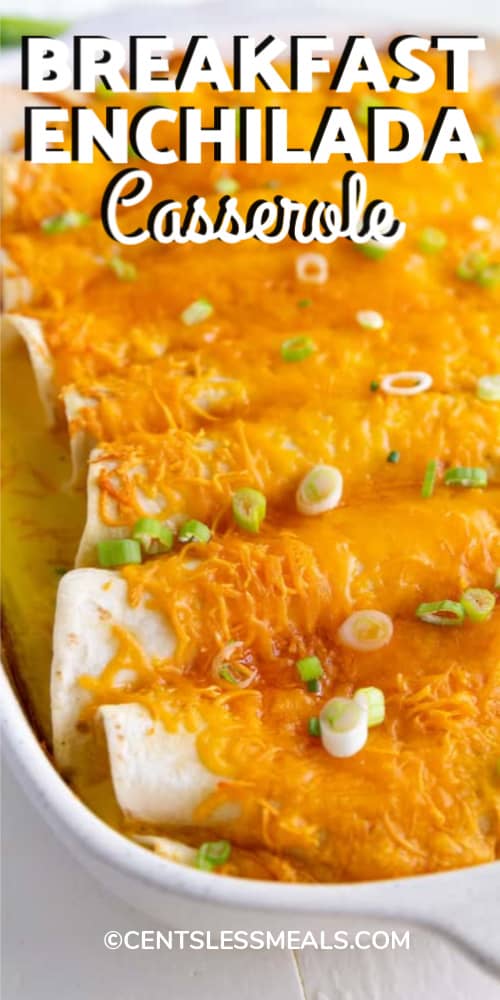 Breakfast Enchiladas garnished with green onion and baked in a white casserole dish with writing