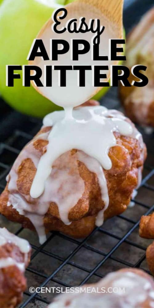 A white glaze being applied with a wooden spoon to Apple Fritters on a cooling rack with a title