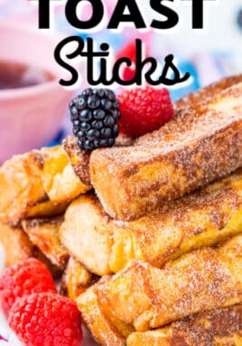 French toast sticks on a white plate with berries and a pink bowl of maple syrup in the background with a title