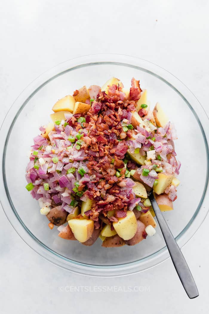 German Potato Salad Recipe ingredients assembled in a clear bowl and ready to be tossed.