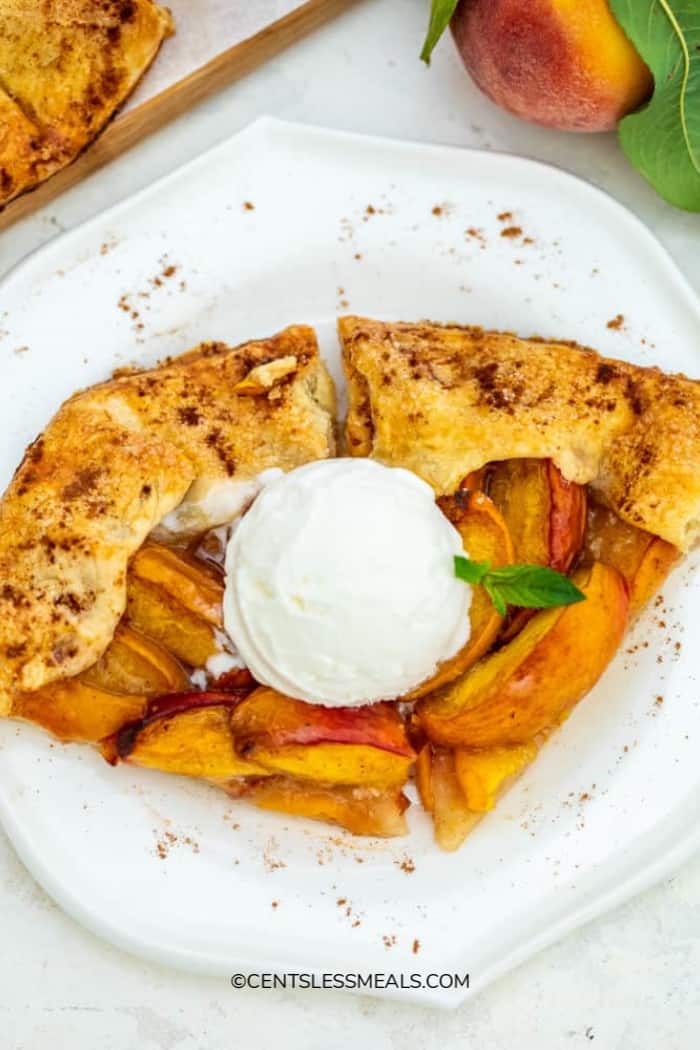 Two slices of peach galette on a plate, topped with ice cream.