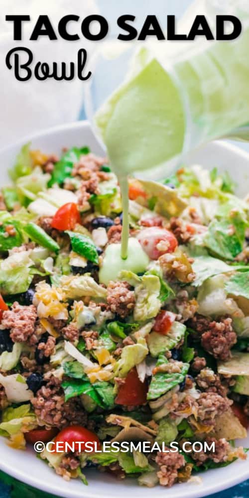 Creamy avocado dressing being poured over a taco salad bowl, with writing.