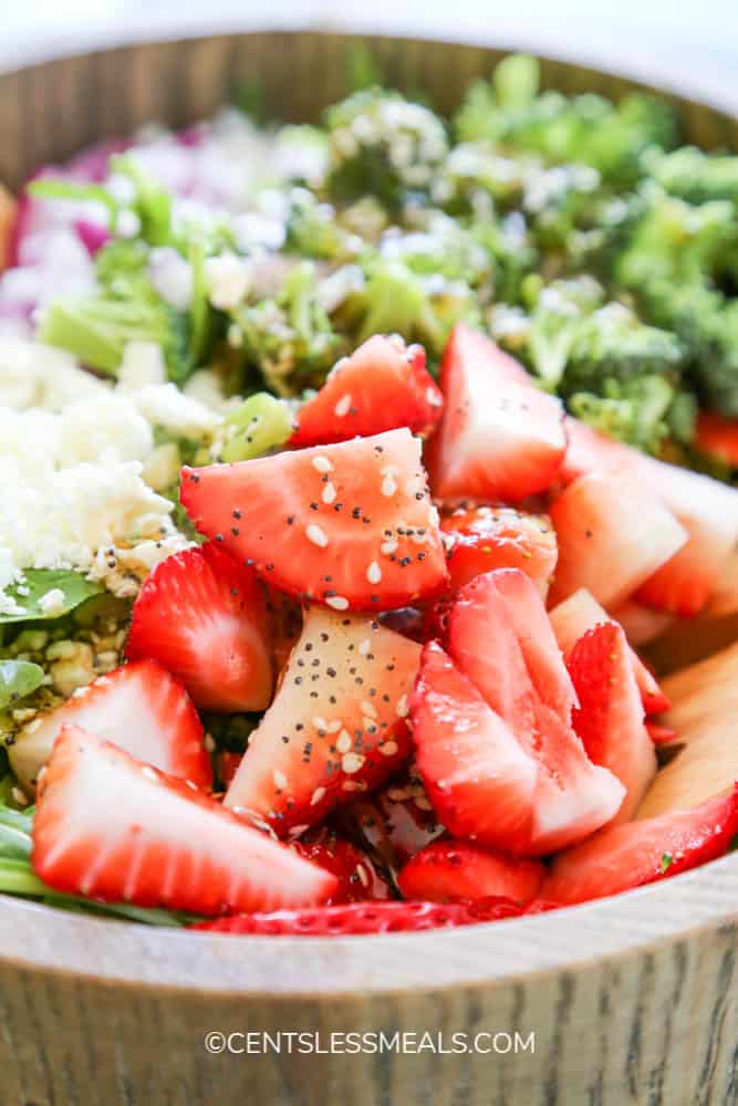 Ingredients for spinach and strawberry salad in a wooden bowl