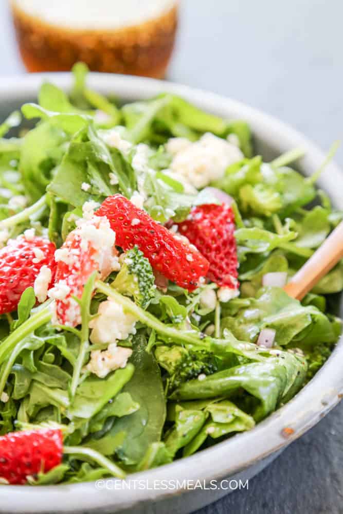 Spinach and strawberry salad in a bowl topped with cheese