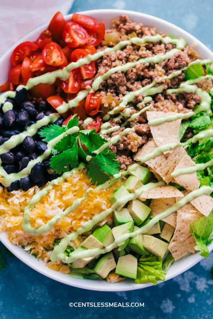 Taco Salad Bowl with creamy avocado dressing drizzled over the top.