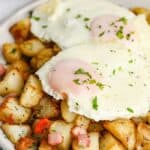 Air Fryer Home Fries on a plate topped with eggs and garnished with fresh parsley