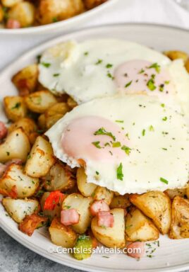 Air Fryer Home Fries on a plate topped with eggs and garnished with fresh parsley