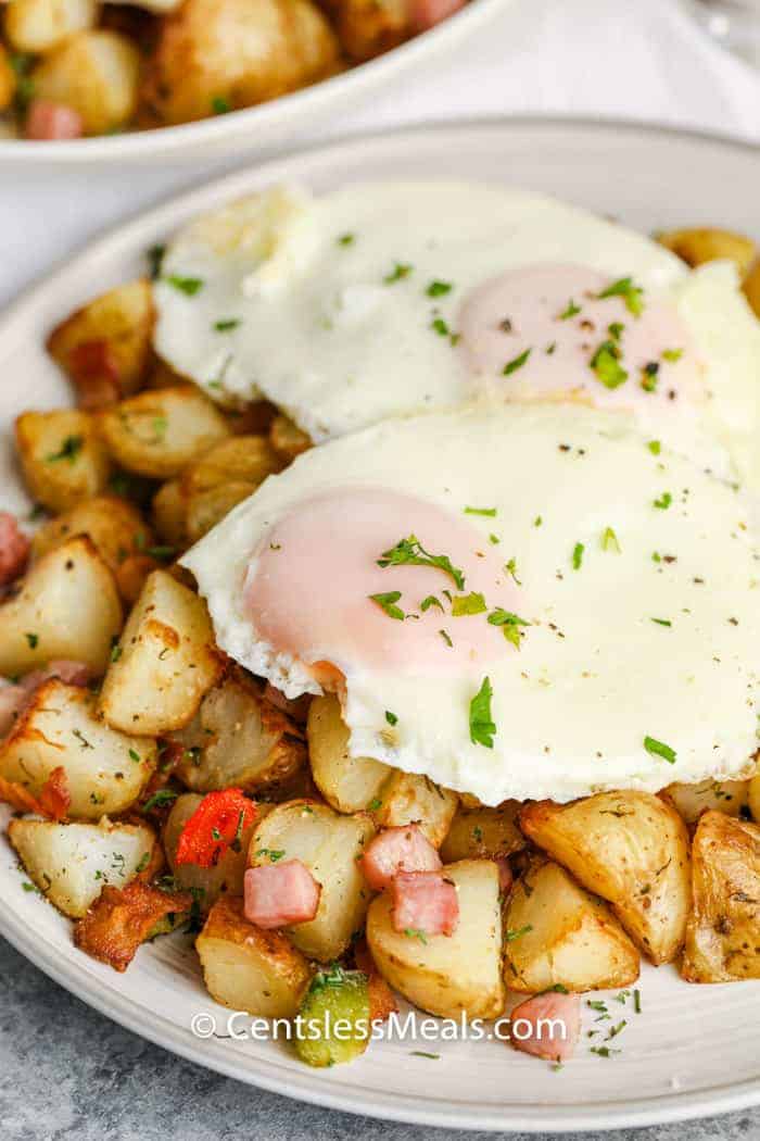 Air Fryer Home Fries on a plate topped with eggs and garnished with fresh parsley