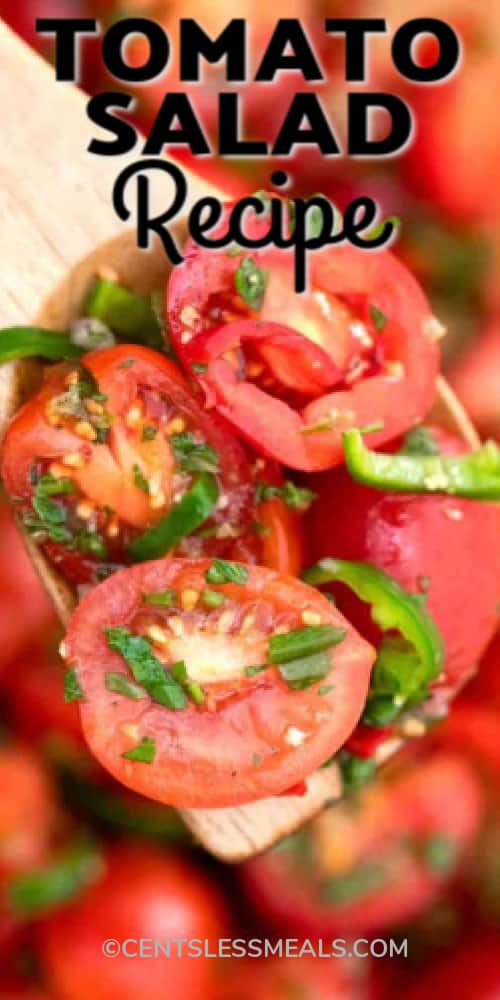 Cherry tomato salad on a wooden spoon with writing.