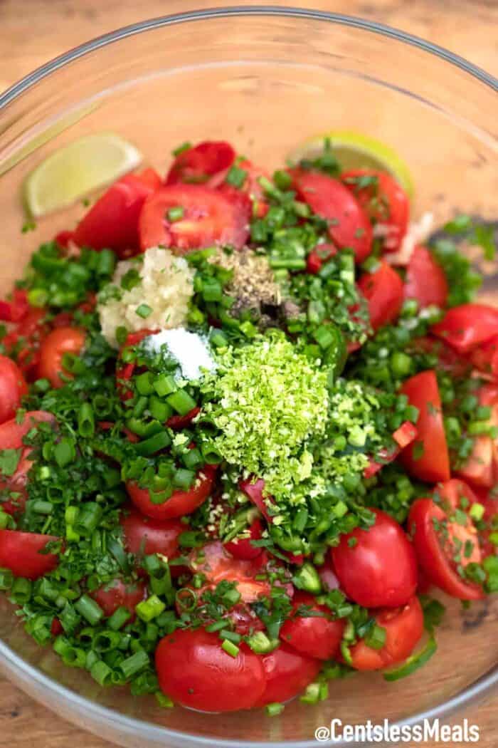 Cherry tomato salad ingredients in a clear bowl.