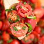 Cherry tomato salad on a wooden spoon.