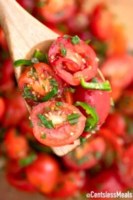 Cherry tomato salad on a wooden spoon.