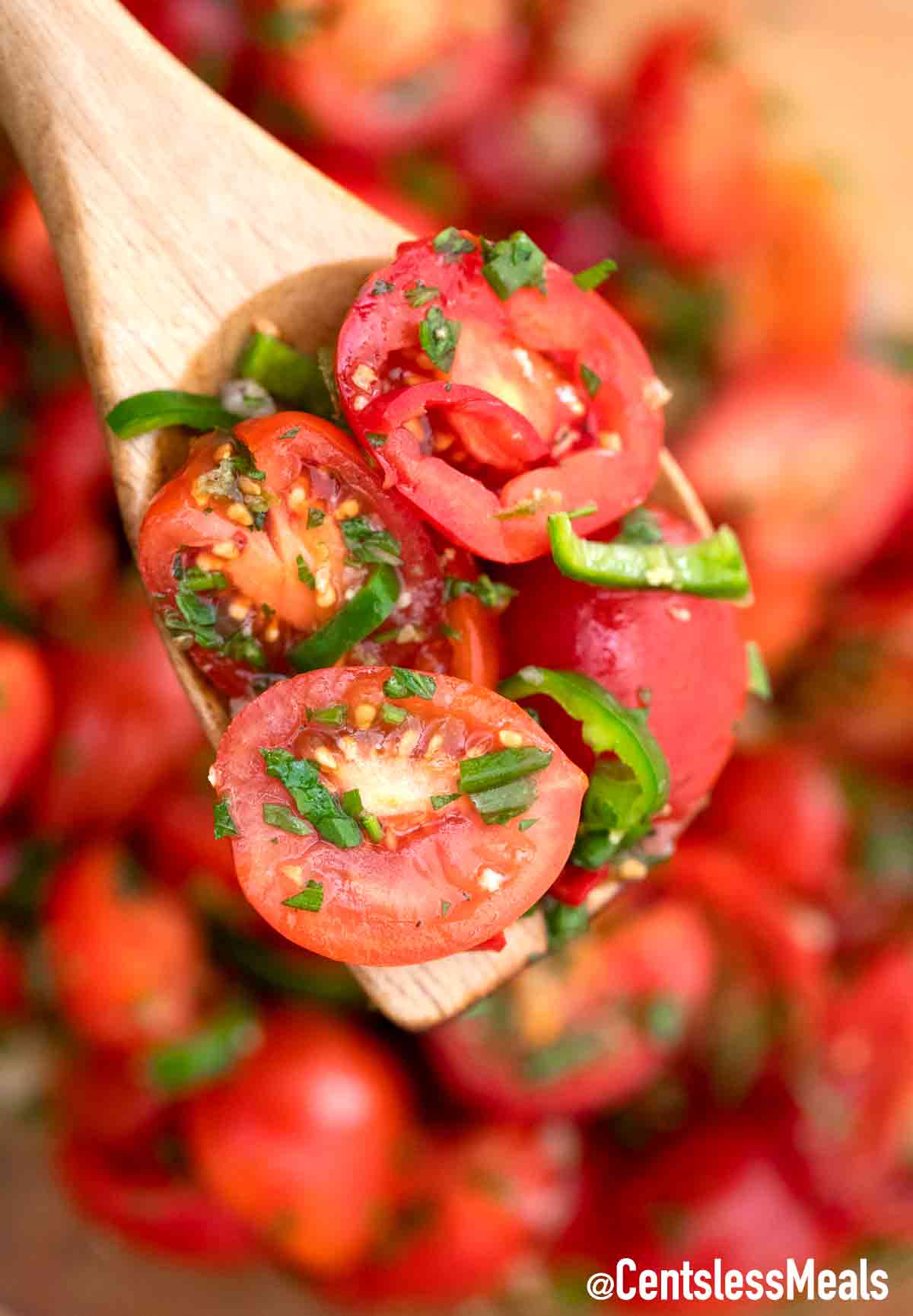 Cherry tomato salad on a wooden spoon.