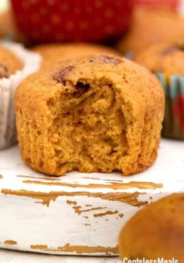 a chocolate chip pumpkin muffin with a bite taken out of it.