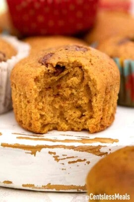 a chocolate chip pumpkin muffin with a bite taken out of it.