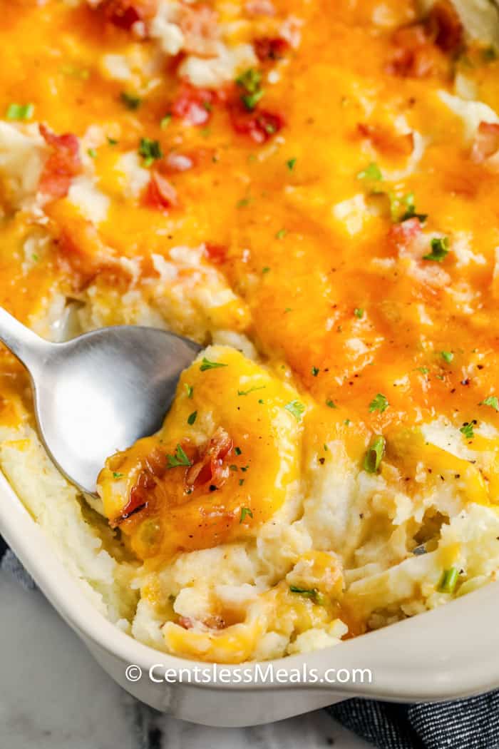 Loaded Mashed Potato Casserole with a spoon taking a bite