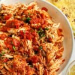 salsa chicken shredded in a bowl with ingredients around the bowl to make Crock Pot Chicken Tacos