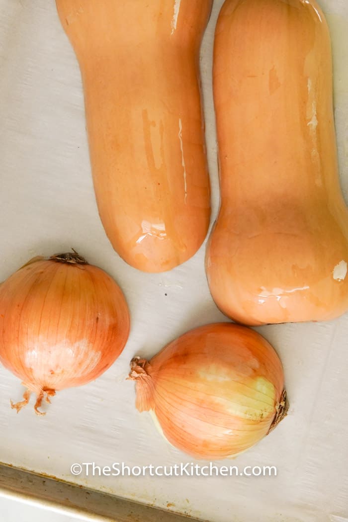 onion and squash on a baking sheet with oil to make Creamy Butternut Squash Soup