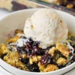 close up of Lemon Blueberry Dump Cake in a bowl with ice cream on top