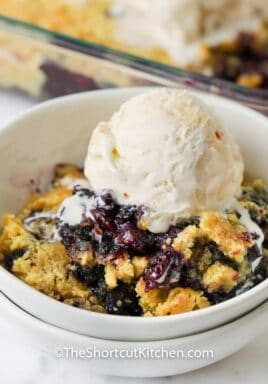 close up of Lemon Blueberry Dump Cake in a bowl with ice cream on top