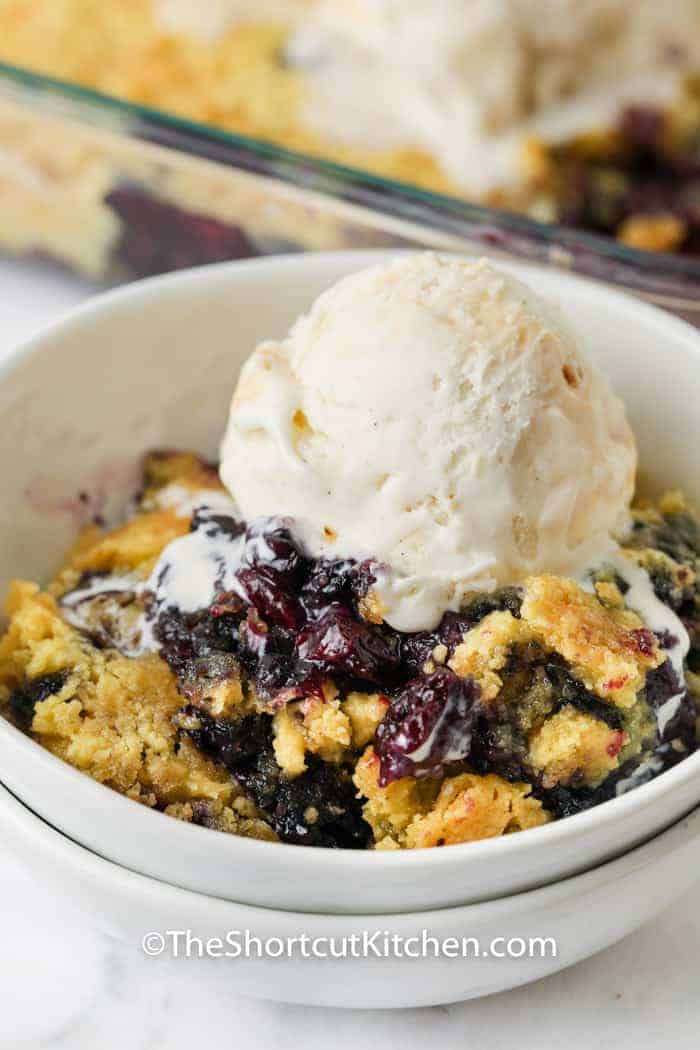 close up of Lemon Blueberry Dump Cake in a bowl with ice cream on top