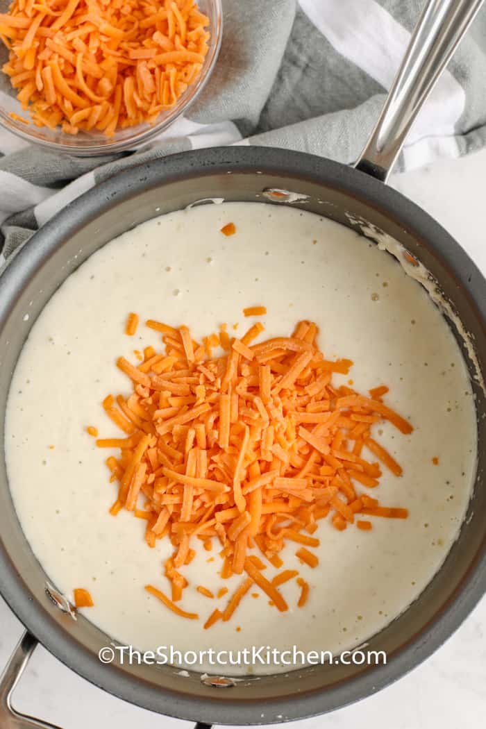 adding cheese to soup mixture in pot to make Creamy Potato Soup