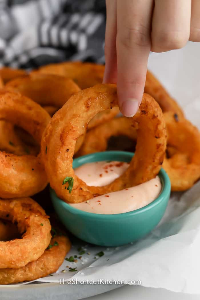 Air Fryer Frozen Onion Rings dipped into sauce