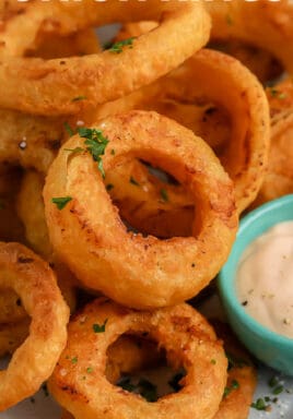 Air Fryer Frozen Onion Rings piled on a plate with dipping sauce on the side with a title