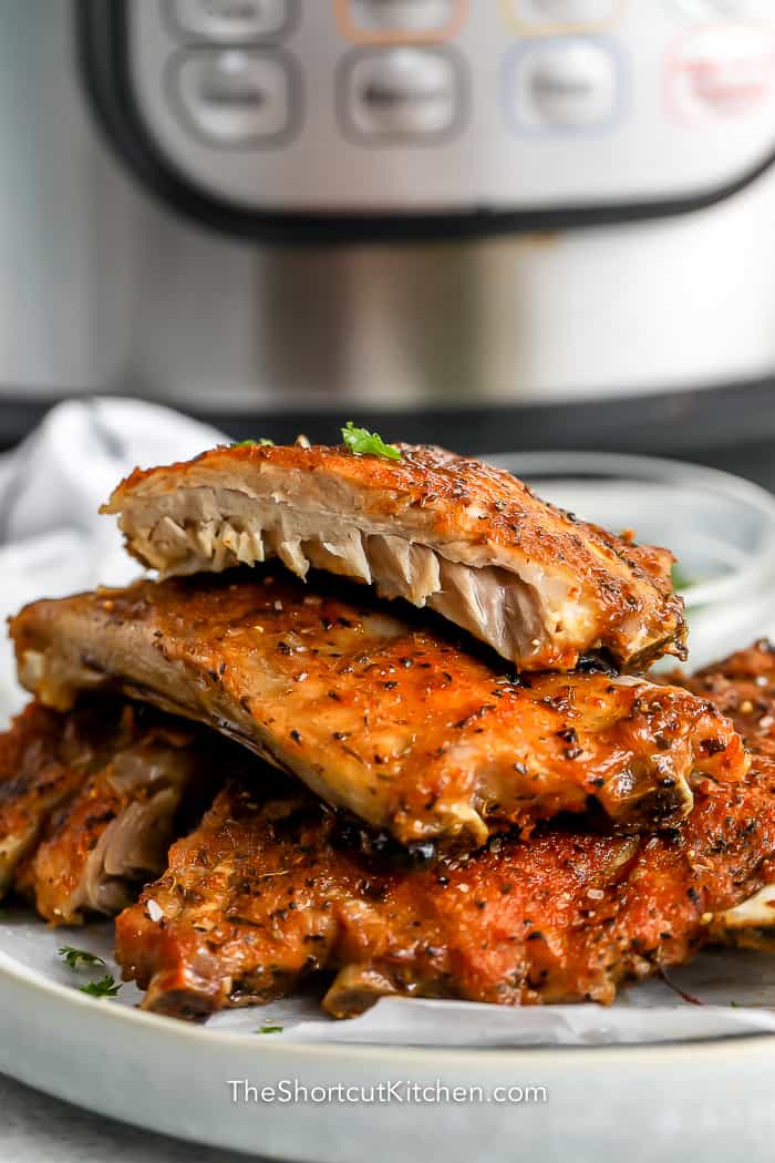 Instant Pot Ribs cut on a plate with an Instant Pot in the background