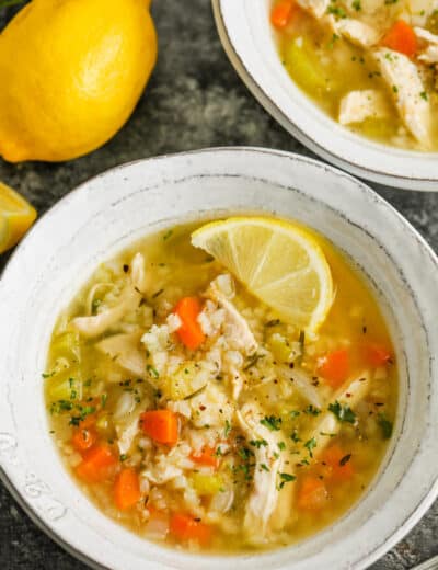 close up of Lemon Chicken Soup in a bowl with lemons beside it