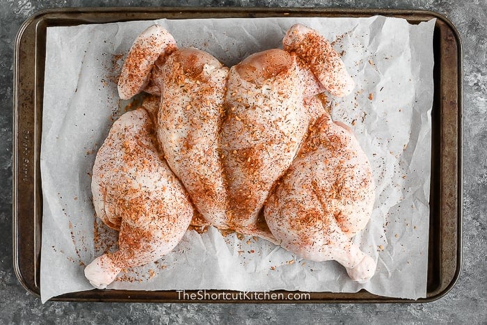 uncooked chicken on tray with seasoning