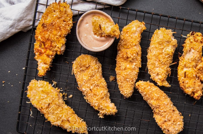Crispy Coconut Chicken Strips on a wire baking rack with dipping sauce