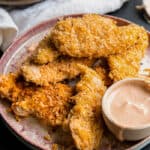 a plate of Crispy Coconut Chicken Strips with sauce