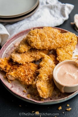 a plate of Crispy Coconut Chicken Strips with sauce