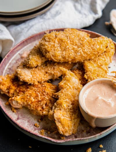 a plate of Crispy Coconut Chicken Strips with sauce