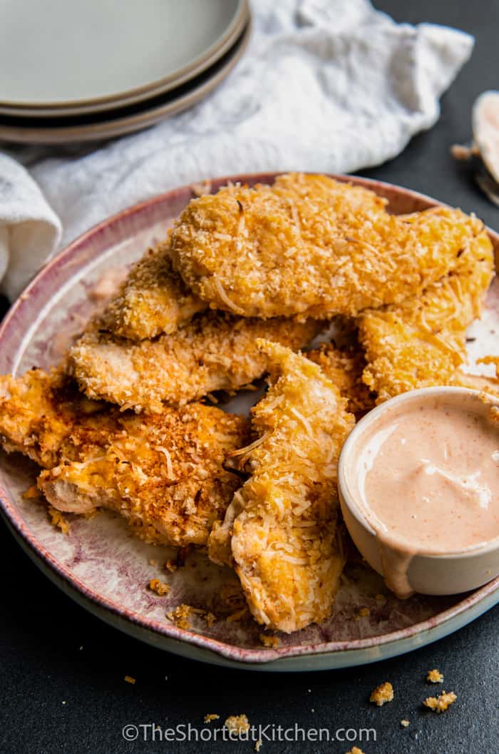 a plate of Crispy Coconut Chicken Strips with sauce