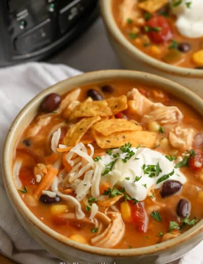 crock pot chicken tortilla soup in bowl topped with sour cream and parsley