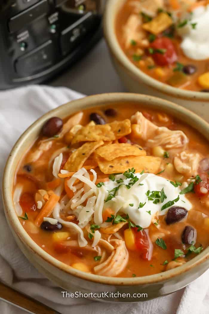 crock pot chicken tortilla soup in bowl topped with sour cream and parsley