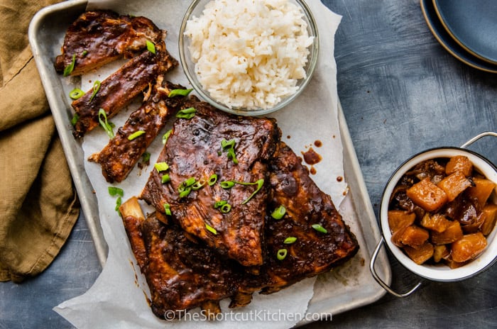 Sweet and spicy crock pot ribs on a baking tray with a side of rice