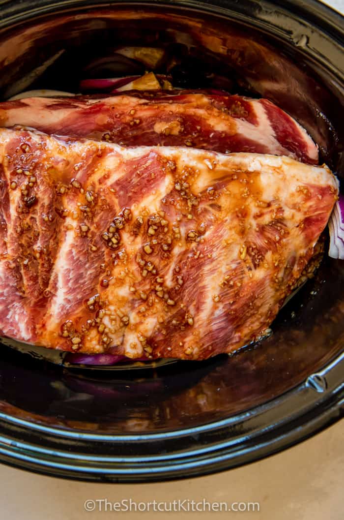 Sweet and spicy sauce poured over ribs in a crock pot.