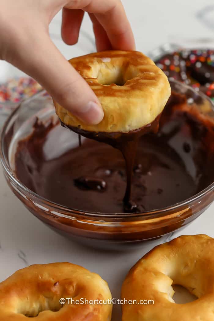 dipping a donut in melted chocolate