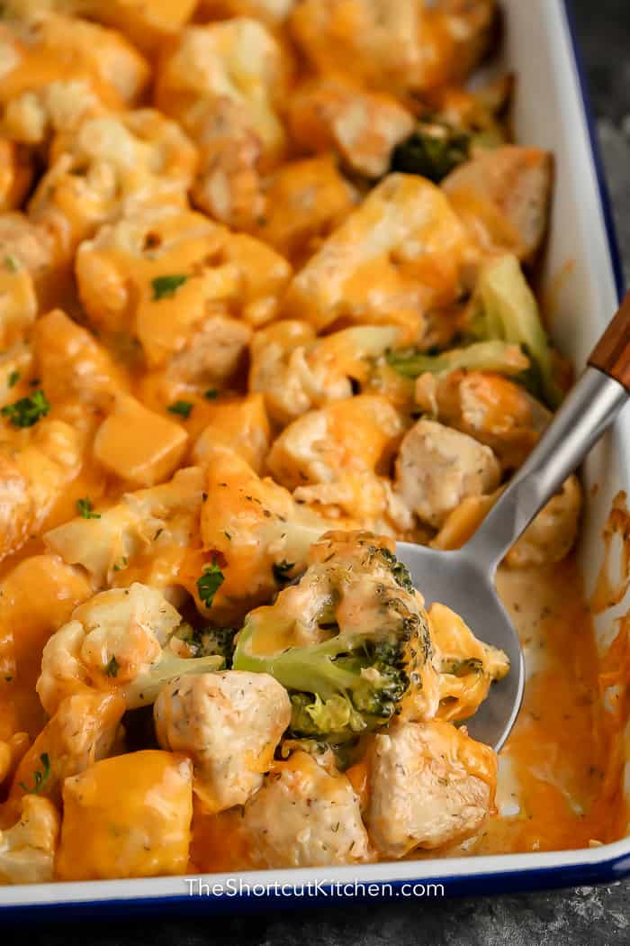 cheesy chicken vegetable casserole in a dish with serving spoon