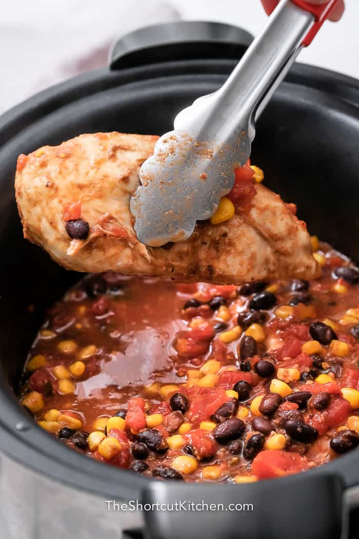 tongs removing chicken from Crockpot