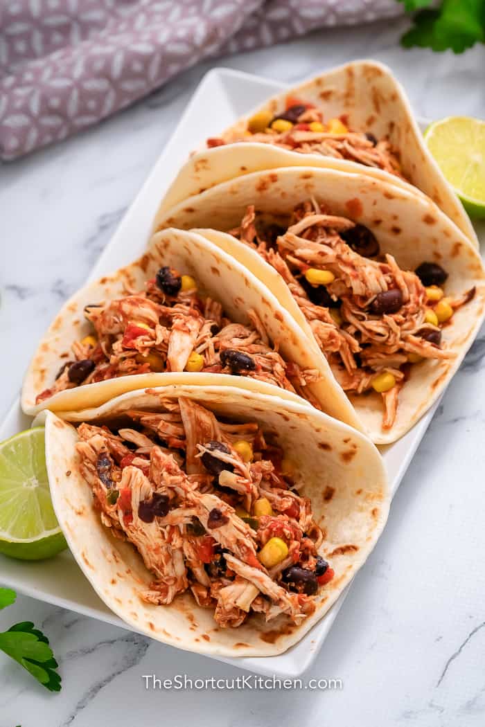 four Crockpot shredded chicken tacos on a plate