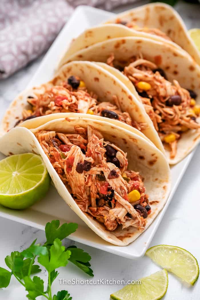 Crockpot shredded chicken tacos on a plate with limes